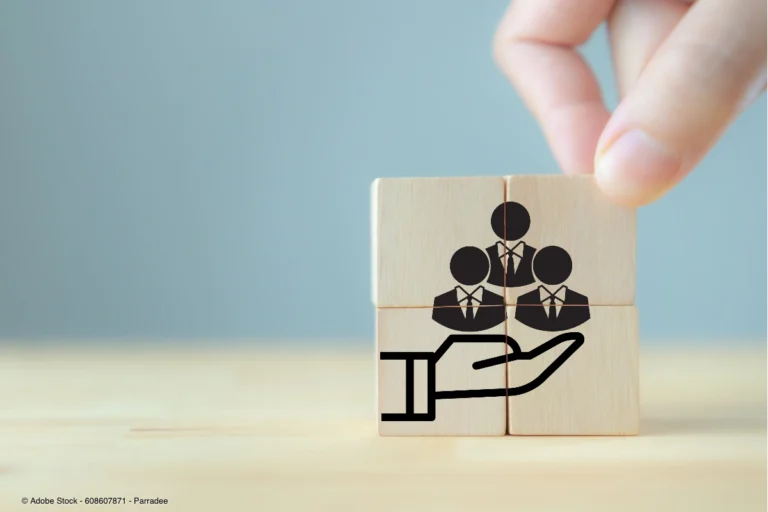 Holzwürfel mit stilisierten Personen symbolisieren Mitarbeiterfürsorge und Zusammenarbeit, passend zum Thema Gesundheitstag im Unternehmen planen und organisieren.